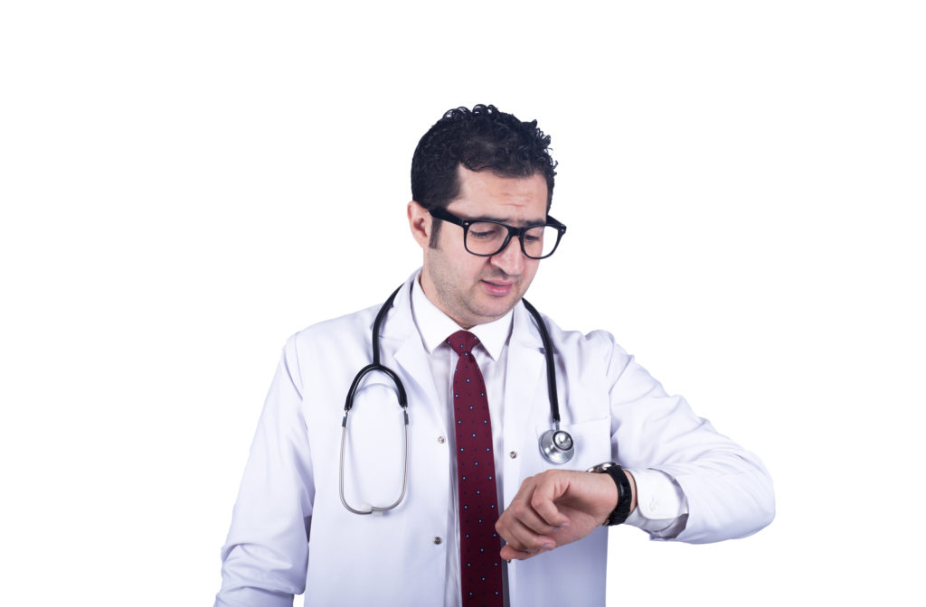 Doctor looking at clock waiting for late patient for appointment.
